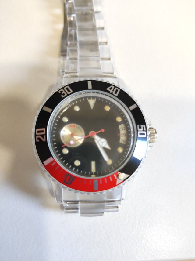 Reloj transparente con detalles en rojo y negro.