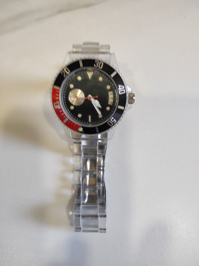 Reloj transparente con detalles en rojo y negro.