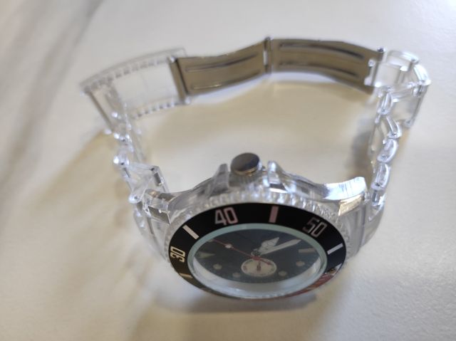 Reloj transparente con detalles en rojo y negro.