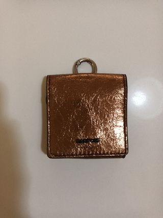 Cartera Parfois dorada con anilla para colgar.