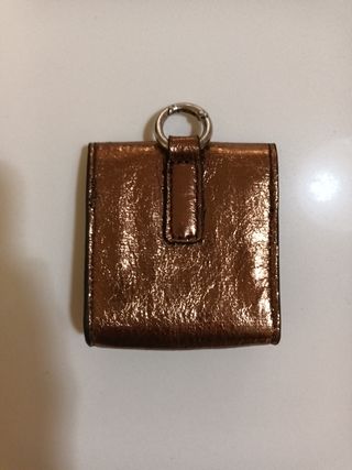 Cartera Parfois dorada con anilla para colgar.