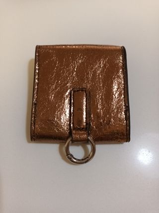Cartera Parfois dorada con anilla para colgar.
