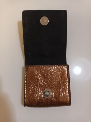 Cartera Parfois dorada con anilla para colgar.