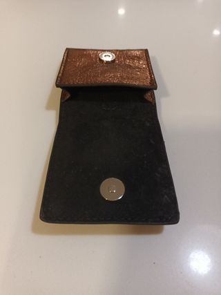 Cartera Parfois dorada con anilla para colgar.