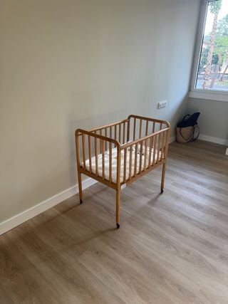Minicuna de madera con ruedas.
