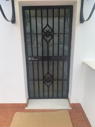 Puerta de hierro con reja decorativa