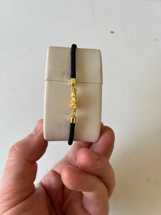Pulsera negra con detalles dorados