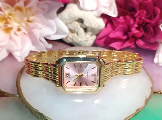 Reloj dorado con esfera rosa