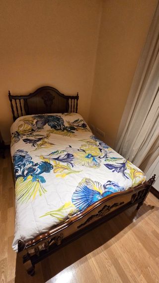 Cama de madera con colchon y colcha floral