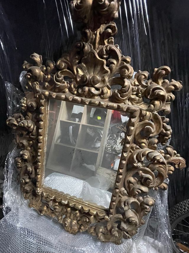 Espejo clásico dorado con marco ornamentado.