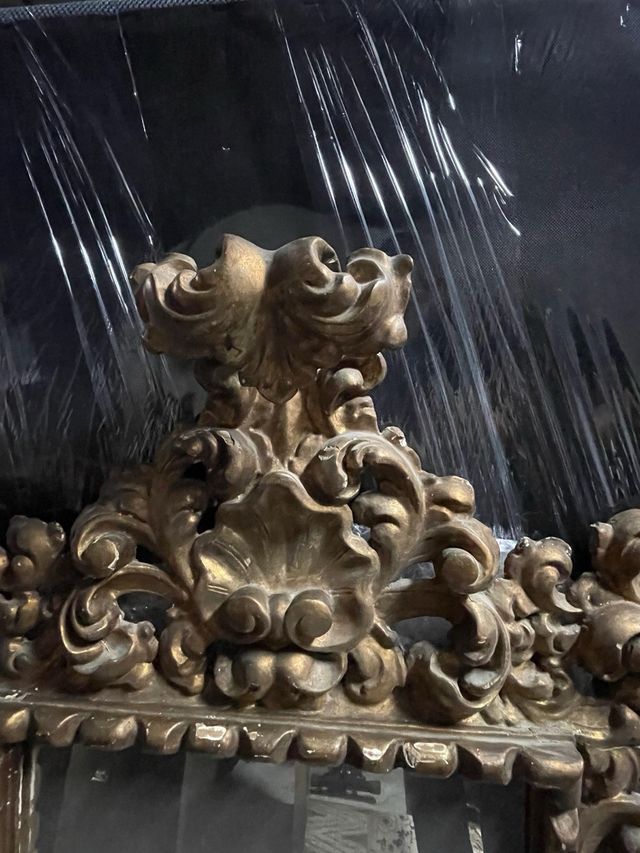 Espejo clásico dorado con marco ornamentado.