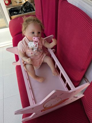 Cuna de muñeca rosa y muñeco