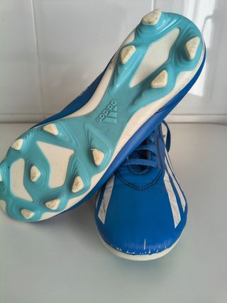 Botas de fútbol con tacos Adidas azules.
