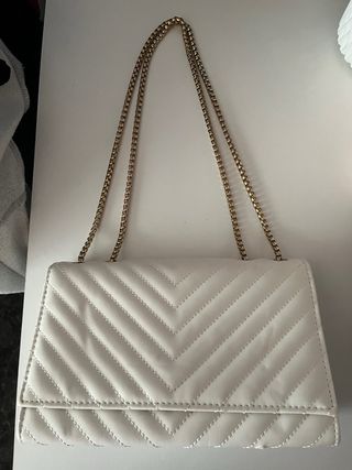 Bolso blanco acolchado con cadena dorada.