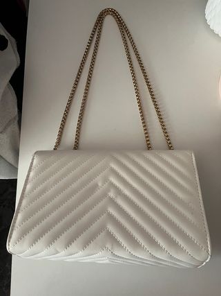 Bolso blanco acolchado con cadena dorada.