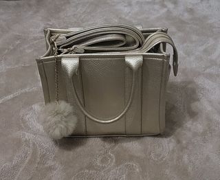 Bolso de mano dorado con pompón