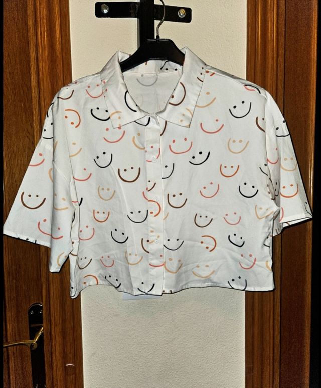 Camisa blanca con estampado de caritas sonrientes.