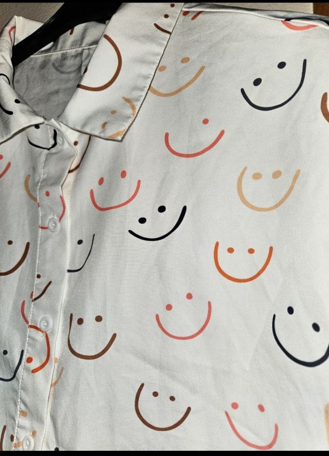 Camisa blanca con estampado de caritas sonrientes.