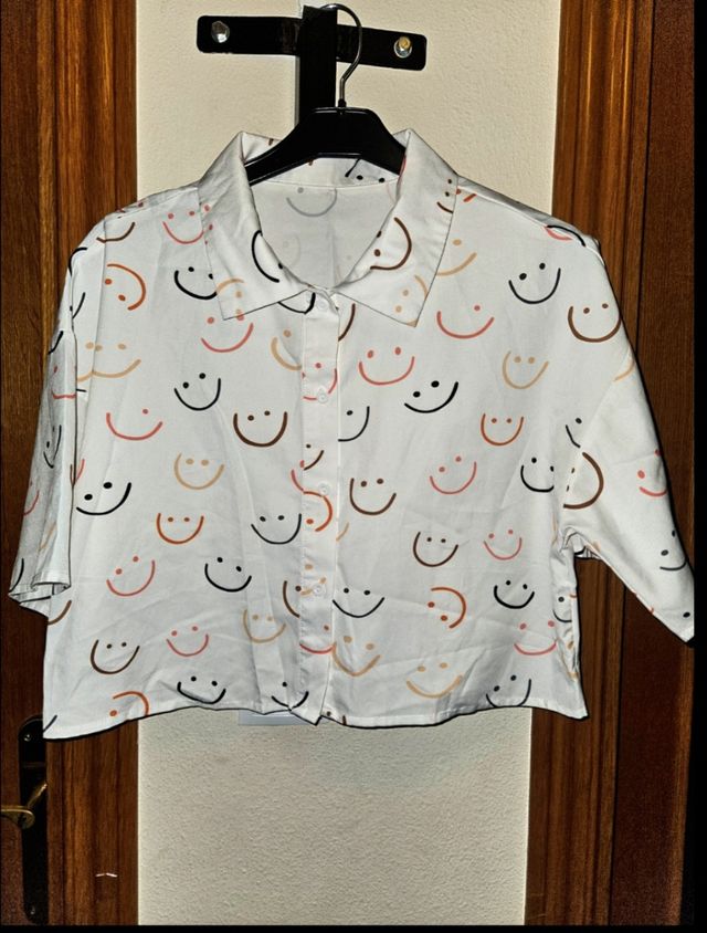 Camisa blanca con estampado de caritas sonrientes.