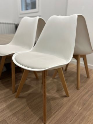 Sillas blancas con patas de madera.