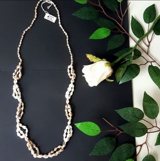 Collar largo de caracolas en tonos crema y beige. 
