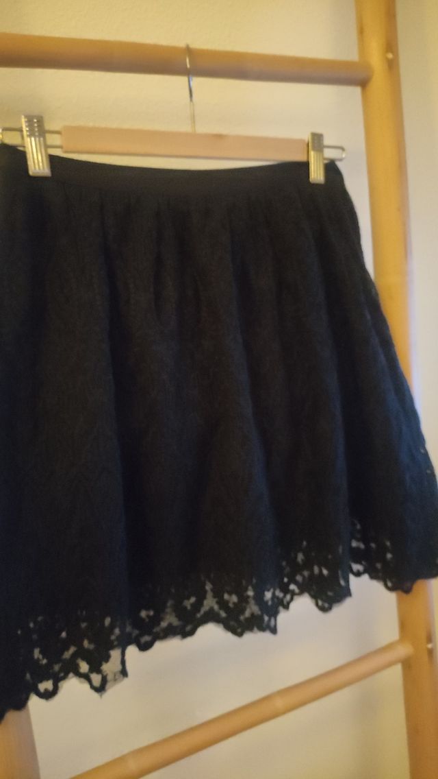 Falda de encaje corta negra.