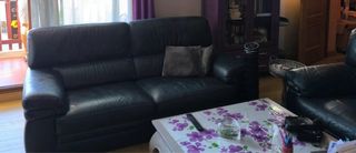 Sofá de cuero negro con sillón y puff