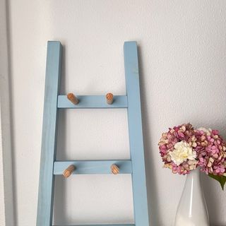 Escalera de madera azul con perchas.
