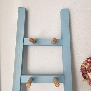 Escalera de madera azul con perchas.