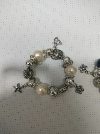Pulseras plateadas con perlas y dijes