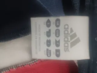 Chaqueta deportiva Adidas azul y rojo.