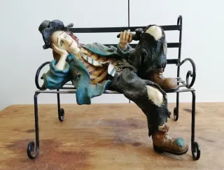 Figura payaso durmiendo en banco