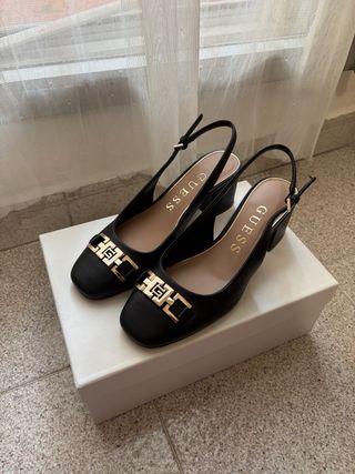 Zapatos tacón Guess negros con detalle dorado. 