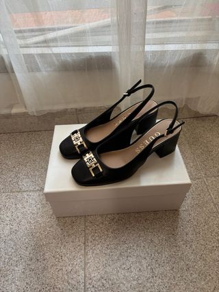 Zapatos tacón Guess negros con detalle dorado. 
