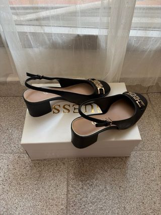 Zapatos tacón Guess negros con detalle dorado. 