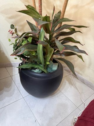 Planta artificial grande con maceta negra.