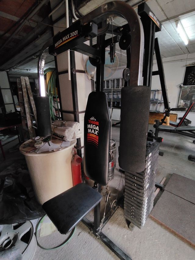 Gimnasio, con una maquina, barras, discos y banco