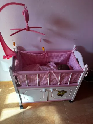 Cuna de muñecas rosa con móvil