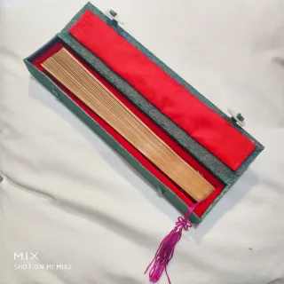 Abanico artesanal de madera de sándalo en su caja.
