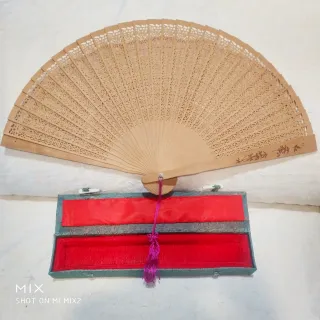 Abanico artesanal de madera de sándalo en su caja.