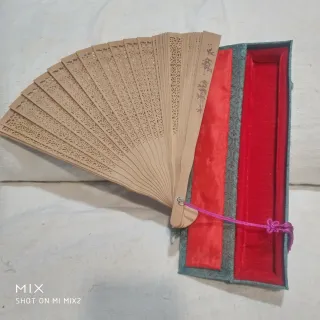 Abanico artesanal de madera de sándalo en su caja.