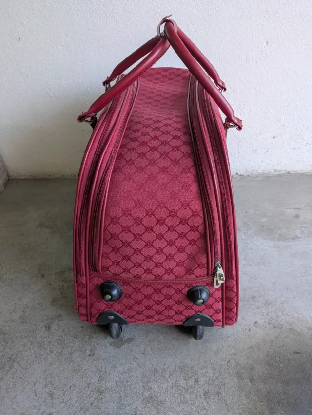 Bolso de viaje de color granate con ruedas.