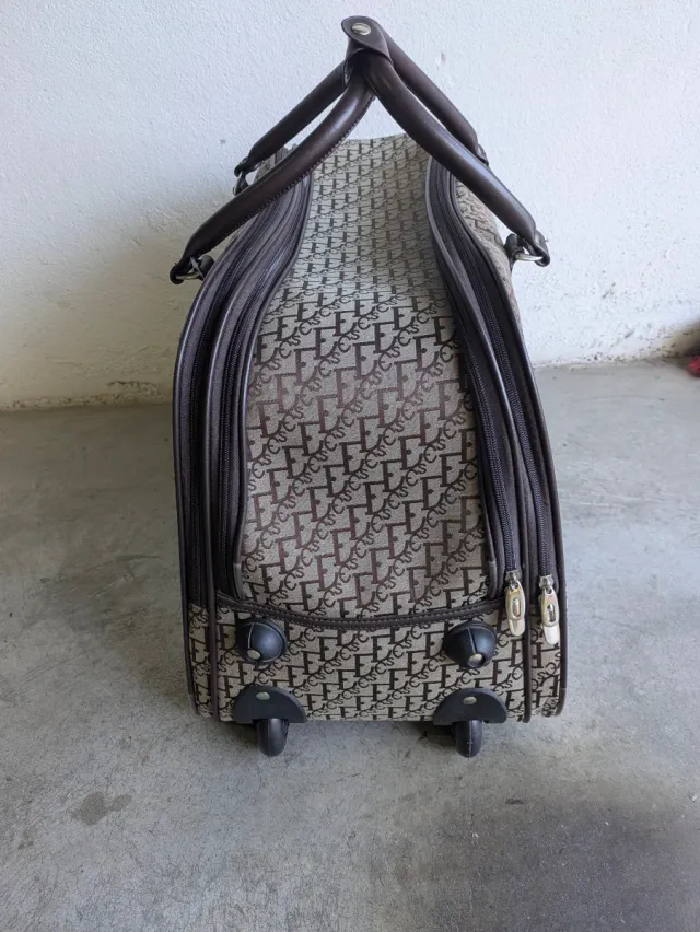 Bolso de viaje beige y marrón con ruedas.