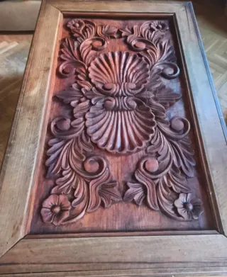 Mesa de madera robusta y labrada, con cristal