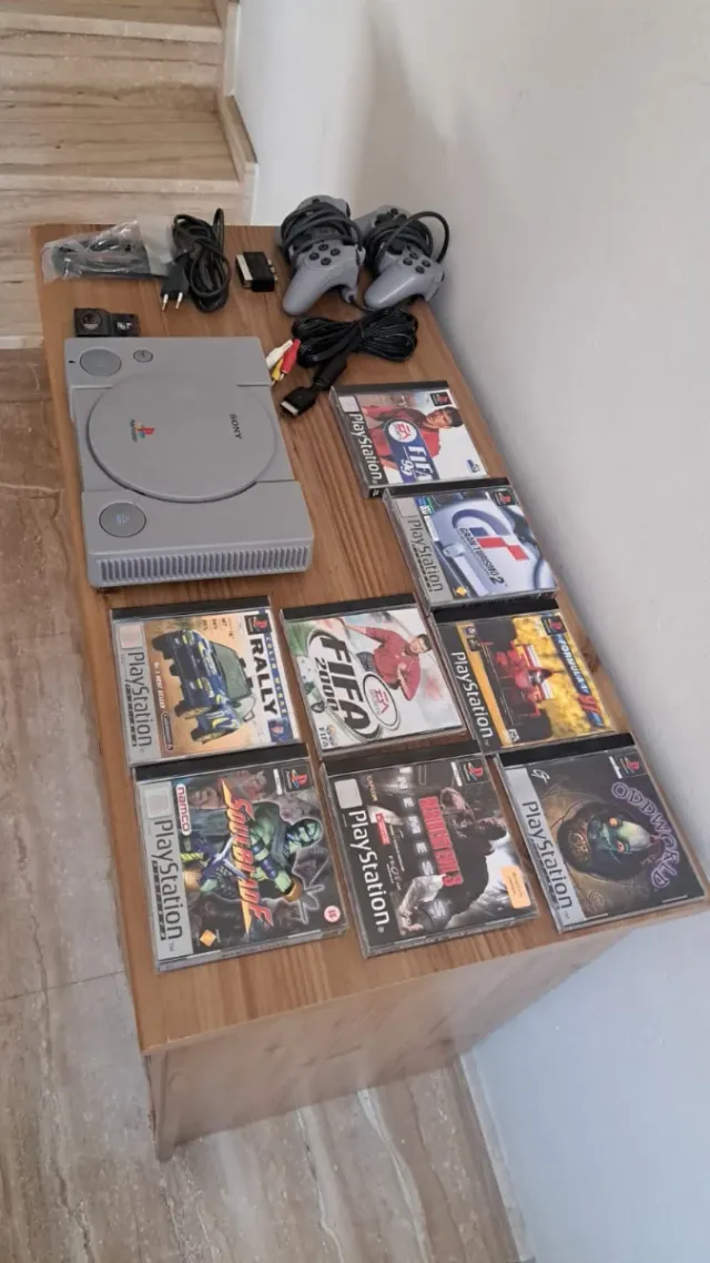 Consola PS1 cinzenta com 2 controlos e 8 jogos. Conjunto.