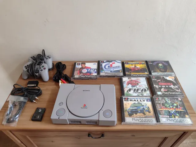 Consola PS1 cinzenta com 2 controlos e 8 jogos. Conjunto.