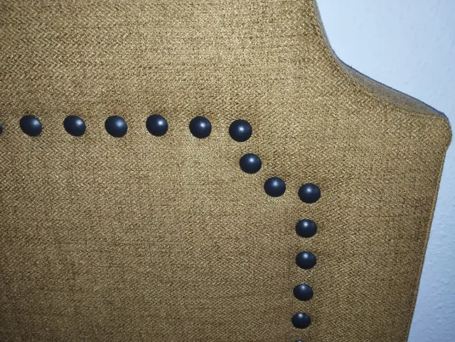 Cabecero de tela mostaza con tachuelas
