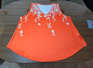 Blusa sin mangas naranja con detalle floral.