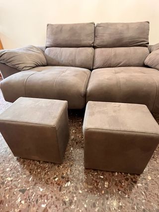 Sofá de tres plazas gris, con 2 puffs