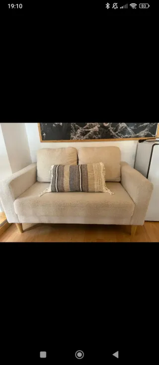 Sofá beige de tela con patas de madera